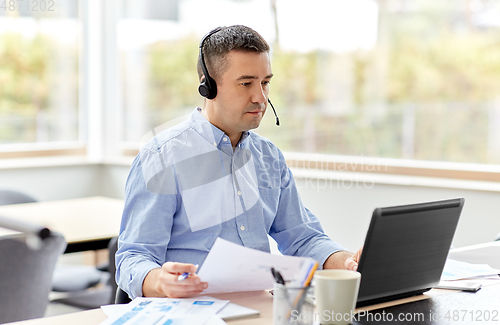 Image of man with headset and laptop working at home