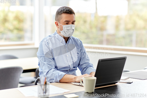 Image of man in mask with laptop working at home office