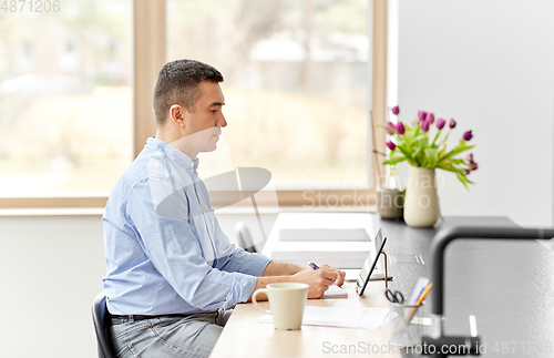 Image of man with tablet computer working at home office