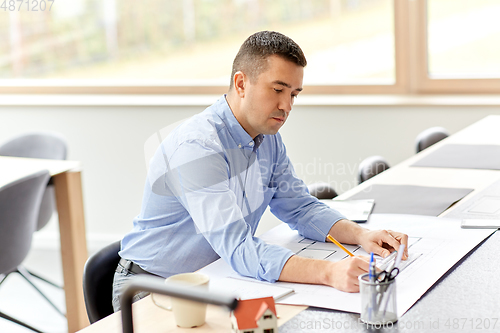 Image of architect with blueprint working at home office