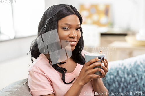 Image of happy african woman drinking tea or coffee at home