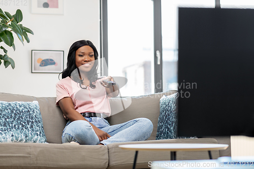 Image of happy african american woman watching tv at home