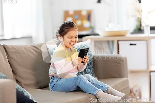 Image of happy smiling little girl with smartphone at home