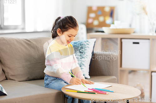 Image of little girl drawing with coloring pencils at home