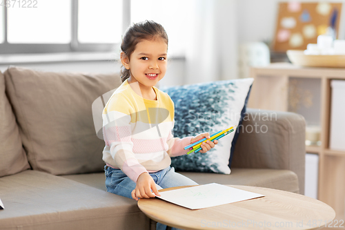 Image of little girl drawing with coloring pencils at home