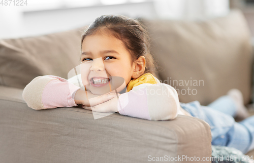 Image of happy smiling little girl lying on sofa at home