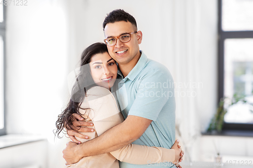 Image of happy couple hugging at home