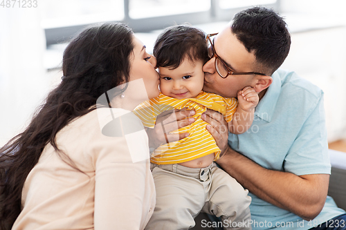 Image of happy mother and father kissing baby son at home