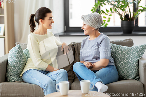 Image of senior mother with adult daughter talking at home