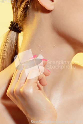 Image of Close up of beautiful woman with melting ice cube over yellow background. Cosmetics and makeup, natural and eco treatment, skin care.