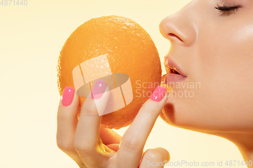 Image of Close up of beautiful female face with orange over yellow background. Cosmetics and makeup, natural and eco treatment, skin care.