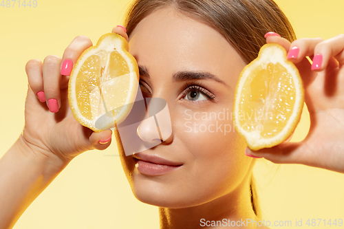 Image of Close up of beautiful female face with lemon slices over yellow background. Cosmetics and makeup, natural and eco treatment, skin care.