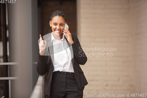 Image of African-american businesswoman in office attire smiling, looks confident and happy, successful