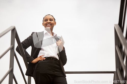 Image of African-american businesswoman in office attire smiling, looks confident and happy, successful