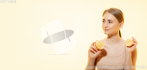 Image of Freshness. Close up of beautiful female face with lemon slices over yellow background. Cosmetics and makeup, natural and eco treatment, skin care. Flyer with copyspace.