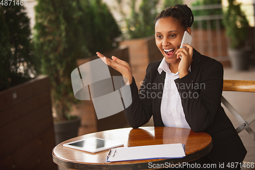 Image of African-american businesswoman in office attire smiling, looks confident and happy, successful