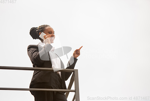 Image of African-american businesswoman in office attire smiling, looks confident and happy, successful