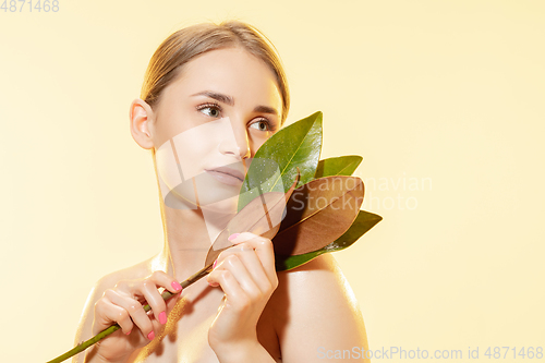Image of Feminine. Close up of beautiful female face with green leaves over white background. Cosmetics and makeup, natural and eco treatment, skin care.