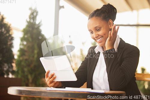 Image of African-american businesswoman in office attire smiling, looks confident and happy, successful