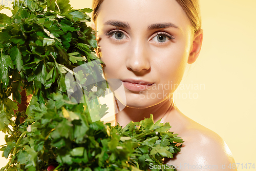 Image of Fresh. Close up of beautiful female face with green leaves over white background. Cosmetics and makeup, natural and eco treatment, skin care.