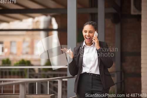 Image of African-american businesswoman in office attire smiling, looks confident and happy, successful