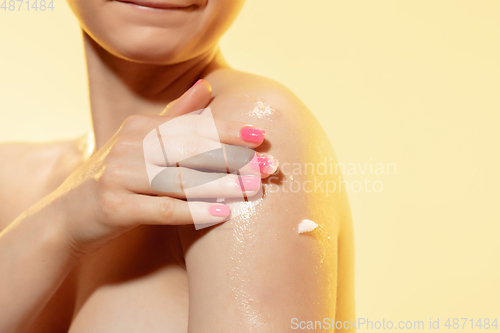 Image of Tender skin. Close up of beautiful woman with moisturizer over yellow background. Cosmetics and makeup, natural and eco treatment, skin care.