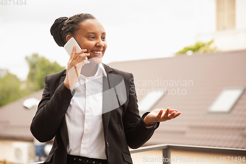 Image of African-american businesswoman in office attire smiling, looks confident and happy, successful