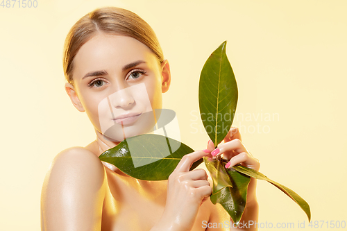 Image of Feminine. Close up of beautiful female face with green leaves over white background. Cosmetics and makeup, natural and eco treatment, skin care.