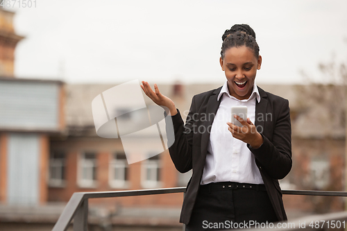 Image of African-american businesswoman in office attire smiling, looks confident and happy, successful