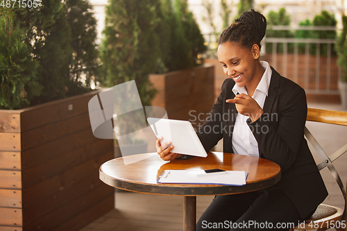 Image of African-american businesswoman in office attire smiling, looks confident and happy, successful