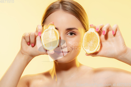 Image of Choosing eco. Close up of beautiful female face with lemon slices over yellow background. Cosmetics and makeup, natural and eco treatment, skin care.