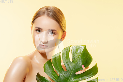 Image of Spa. Close up of beautiful female face with green leaves over white background. Cosmetics and makeup, natural and eco treatment, skin care.