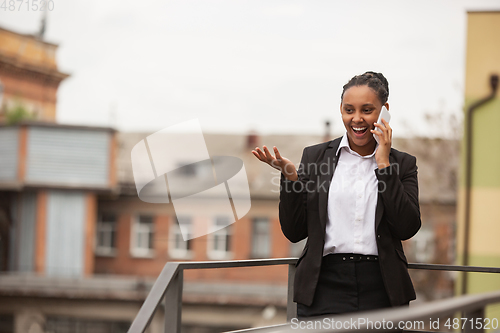 Image of African-american businesswoman in office attire smiling, looks confident and happy, successful