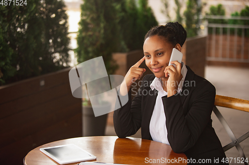 Image of African-american businesswoman in office attire smiling, looks confident and happy, successful