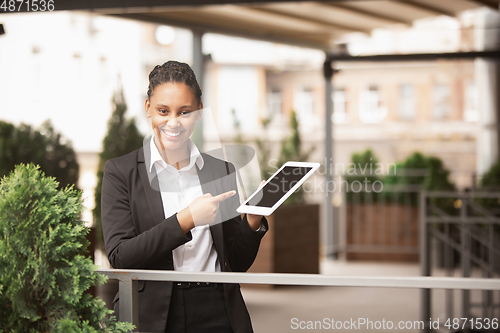 Image of African-american businesswoman in office attire smiling, looks confident and happy, successful