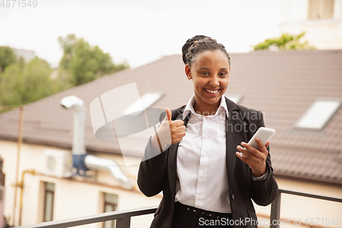 Image of African-american businesswoman in office attire smiling, looks confident and happy, successful