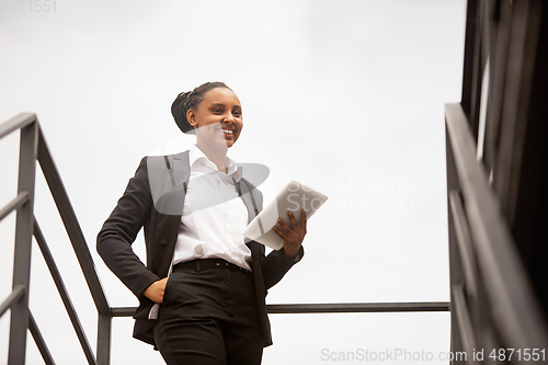 Image of African-american businesswoman in office attire smiling, looks confident and happy, successful