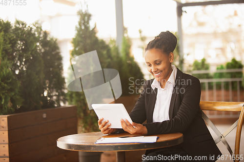 Image of African-american businesswoman in office attire smiling, looks confident and happy, successful