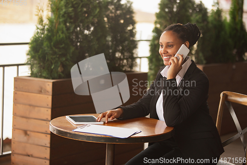 Image of African-american businesswoman in office attire smiling, looks confident and happy, successful