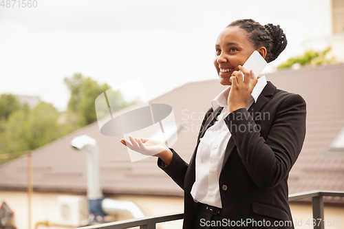 Image of African-american businesswoman in office attire smiling, looks confident and happy, successful