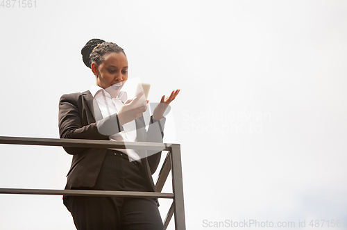 Image of African-american businesswoman in office attire smiling, looks confident and happy, successful