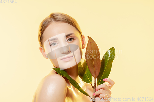 Image of Feminine. Close up of beautiful female face with green leaves over white background. Cosmetics and makeup, natural and eco treatment, skin care.