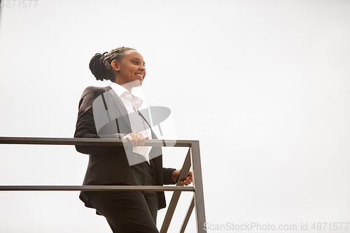 Image of African-american businesswoman in office attire smiling, looks confident and happy, successful