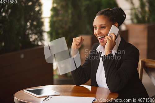 Image of African-american businesswoman in office attire smiling, looks confident and happy, successful