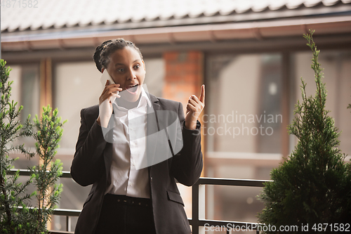 Image of African-american businesswoman in office attire smiling, looks confident and happy, successful