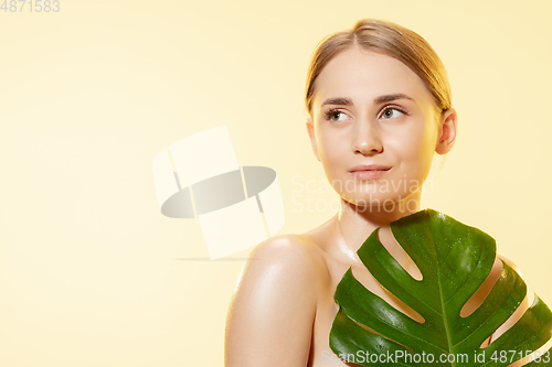 Image of Spa. Close up of beautiful female face with green leaves over white background. Cosmetics and makeup, natural and eco treatment, skin care.