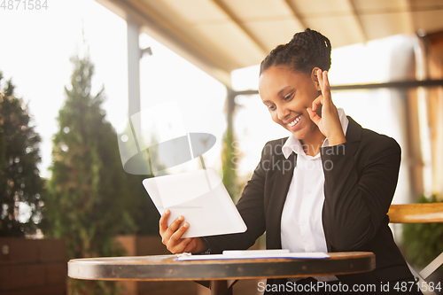 Image of African-american businesswoman in office attire smiling, looks confident and happy, successful