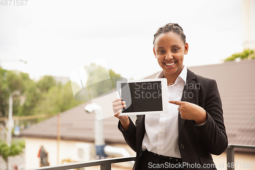 Image of African-american businesswoman in office attire smiling, looks confident and happy, successful