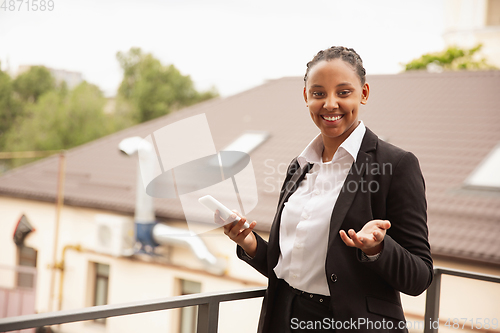 Image of African-american businesswoman in office attire smiling, looks confident and happy, successful