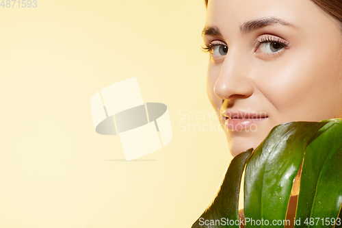 Image of Look. Close up of beautiful female face with green leaves over white background. Cosmetics and makeup, natural and eco treatment, skin care.